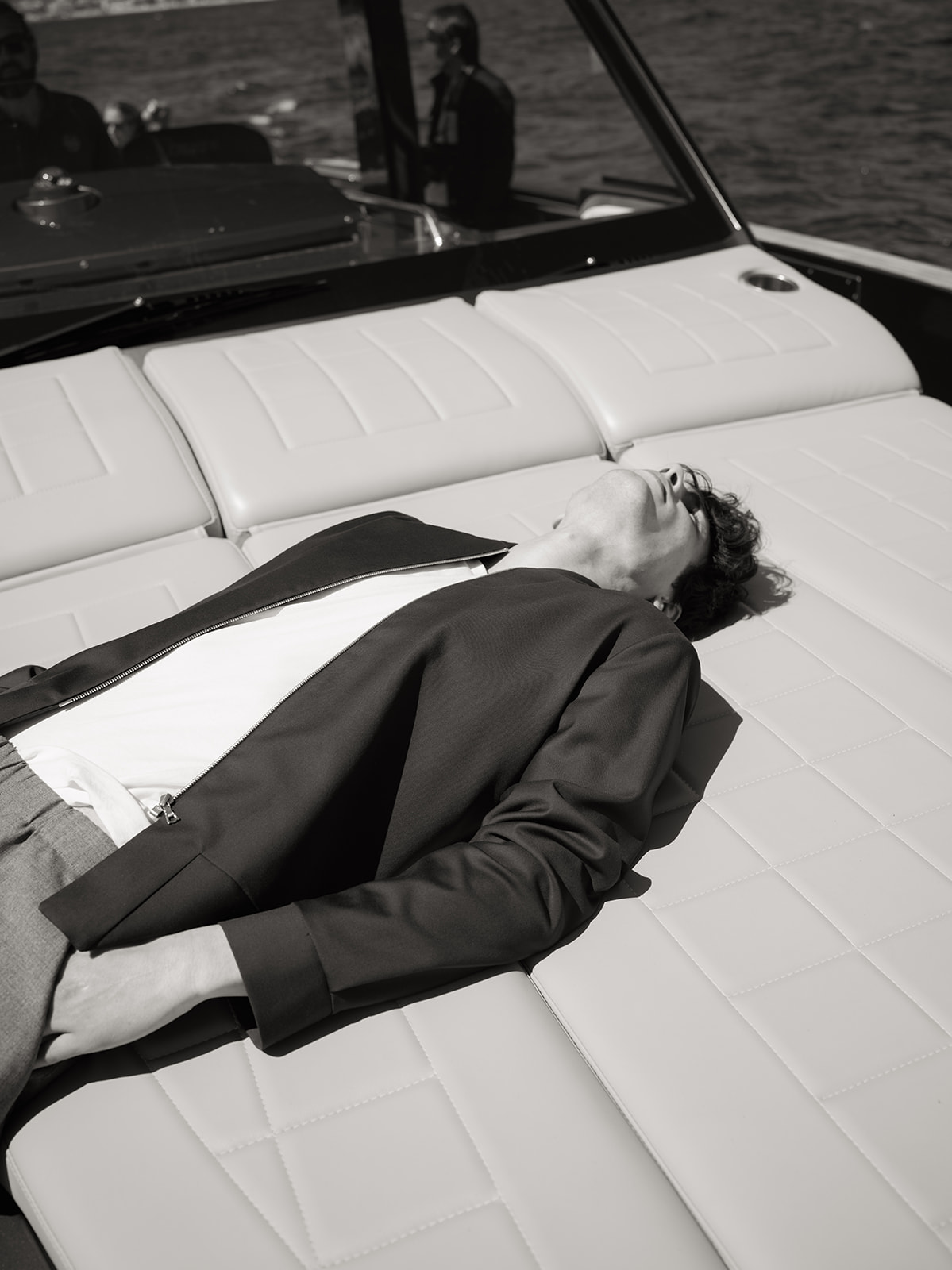 Black-and-white male fashion portrait reclining on a yacht in Saint-Tropez